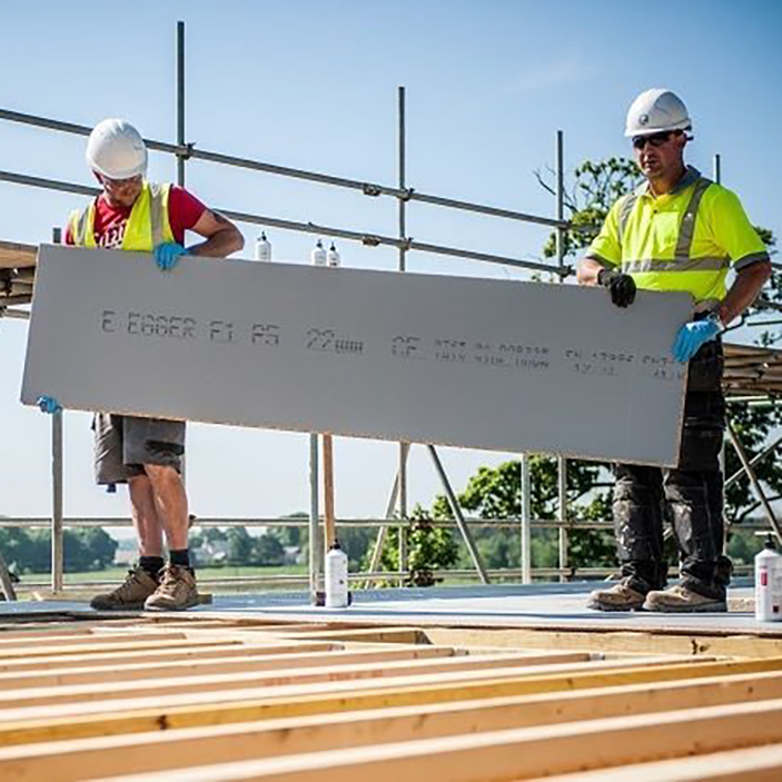 Two builders installing chipboard flooring