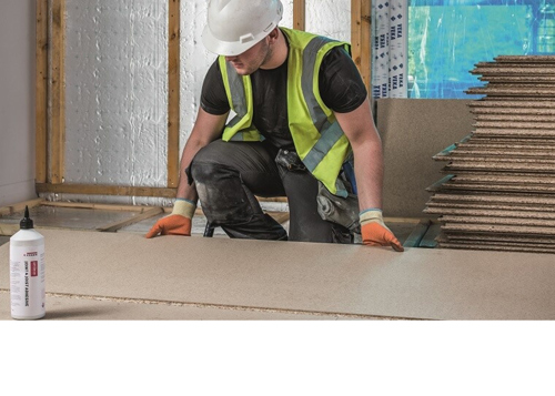 Construction worker laying chipboard flooring